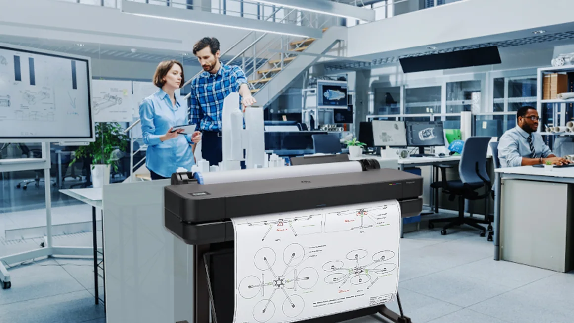 Інженери біля плотера HP DesignJet із надрукованим кресленням у інженерному офісі